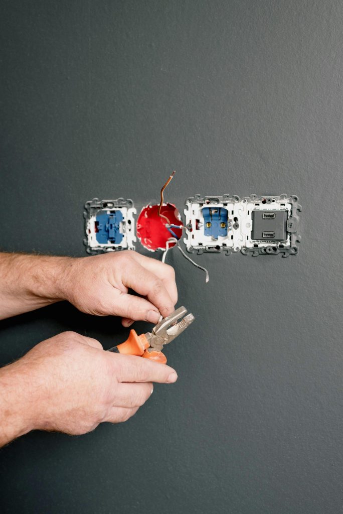 manos arreglando un conector eléctrico en la pared